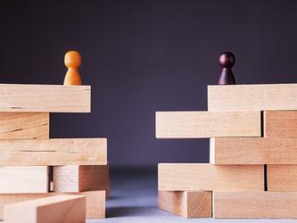 Two wooden figurines positioned on wooden blocks with a gap between them